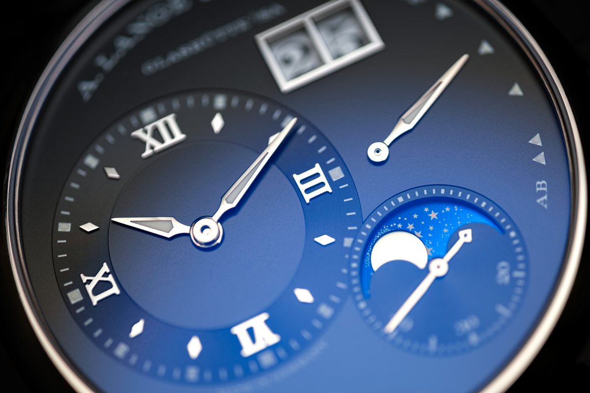 Close-up of a blue watch dial with separate time, date and moon-phase displays